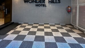 A hotel entrance with a checkered floor, a wall-mounted sign reading "WONDER HILLS HOTEL," and a fire extinguisher on the right. - Hotel Wonder Hills @ Har ki Pauri Road Haridwar (Haridwar)