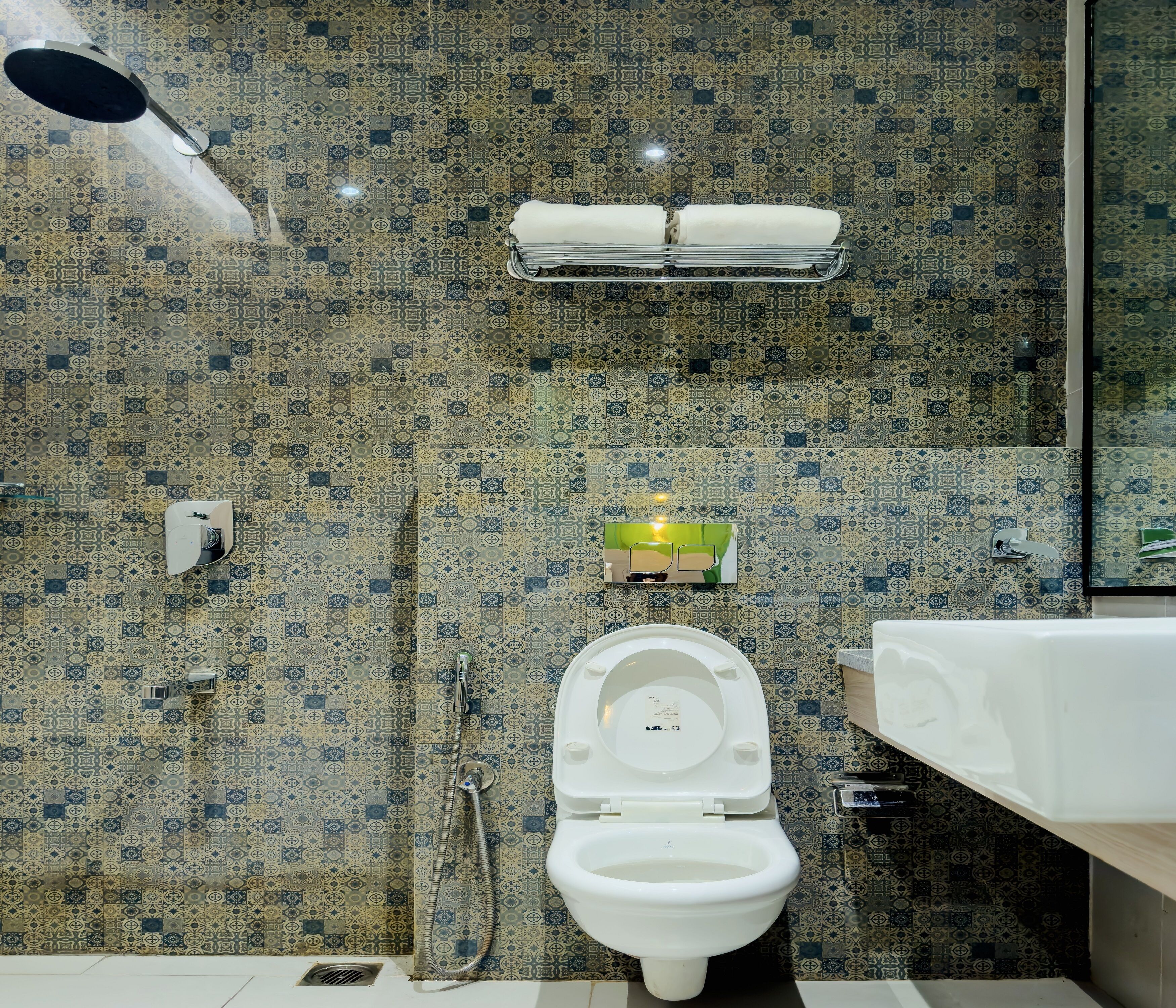 Un baño con pared de azulejos estampados, inodoro, ducha y lavamanos.