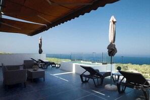 Une terrasse sur le toit avec des espaces salons extérieurs, une piscine et une vue sur la mer.