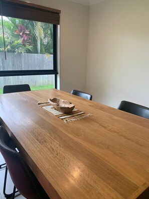 Enjoy meals at a spacious dining table with four chairs, surrounded by a serene view of lush greenery.