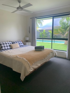 Relax in this inviting room with a large bed, ceiling fan, and a window overlooking the pool and lush surroundings.