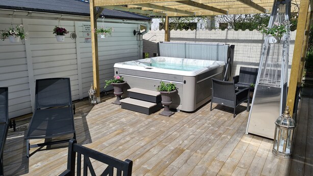 A hot tub under a pergola with outdoor seating and potted plants. - TG Oasis Örgryte Stugor & Rum (Gothenburg)