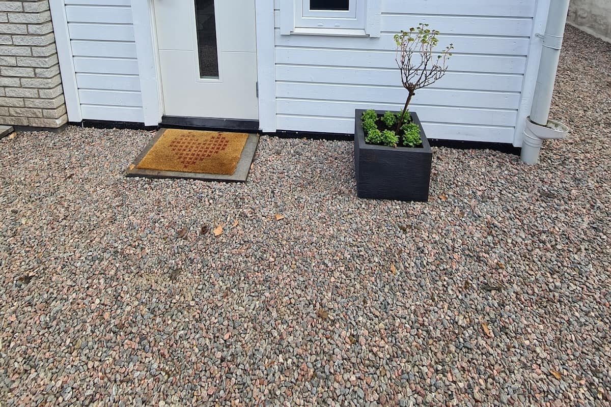 A small, white building with a door marked with the number 8, a small window, and a potted plant.