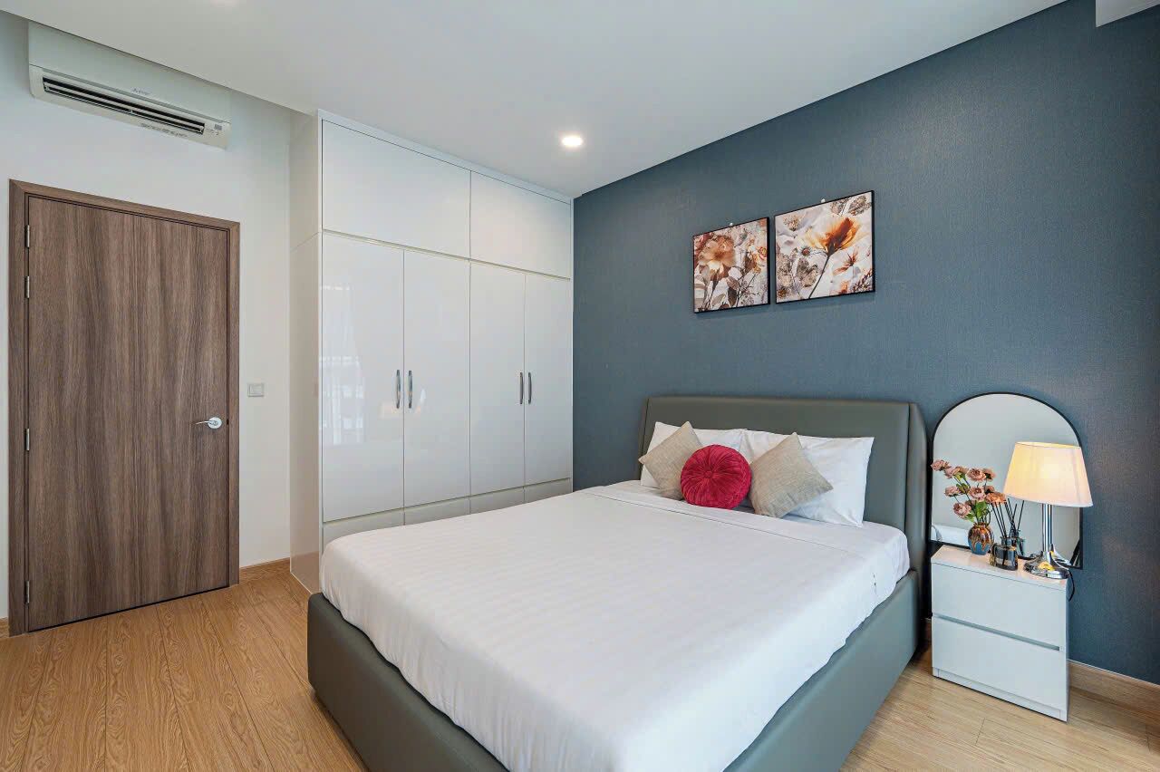 Un dormitorio con una cama, una mesita de noche, un armario y dos obras de arte colgadas en la pared.