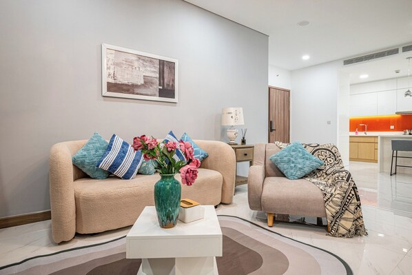 A modern living room with two sofas, a coffee table, and a vase of flowers. - Luxury Sunwah Apartment near Landmark 81 - City View (Ho Chi Minh City)