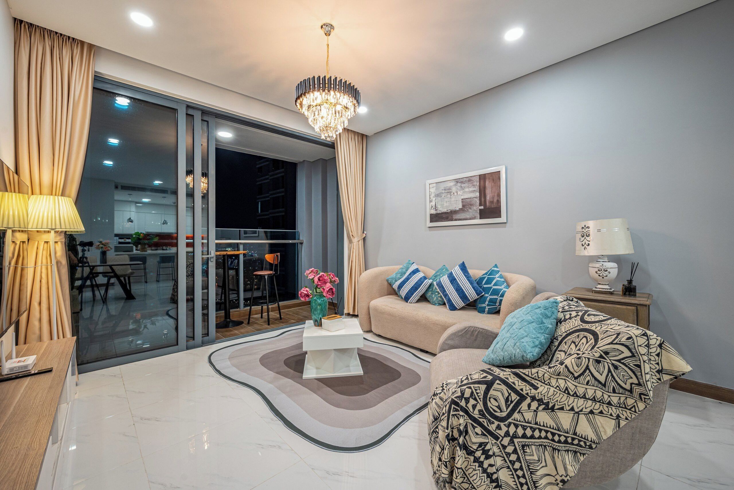 A modern living room with a sofa, patterned armchair, and a coffee table with flowers.