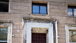 A building with a central entrance featuring a dark wooden door, flanked by stone walls and two windows. - HOUSE OF PRINCE AMBA ALAGI (ST. MARITIME) GENOVABNB.IT (GENOVA)