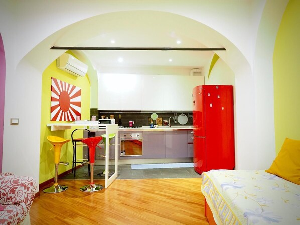 A compact living space with a kitchenette, a dining area, and a bedroom.