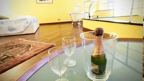 Een kamer met een bed, een tafeltje met een fles champagne en twee lege glazen.