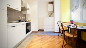 Een moderne keuken met witte kastjes, een fornuis en een eethoek met een houten tafel en stoelen.