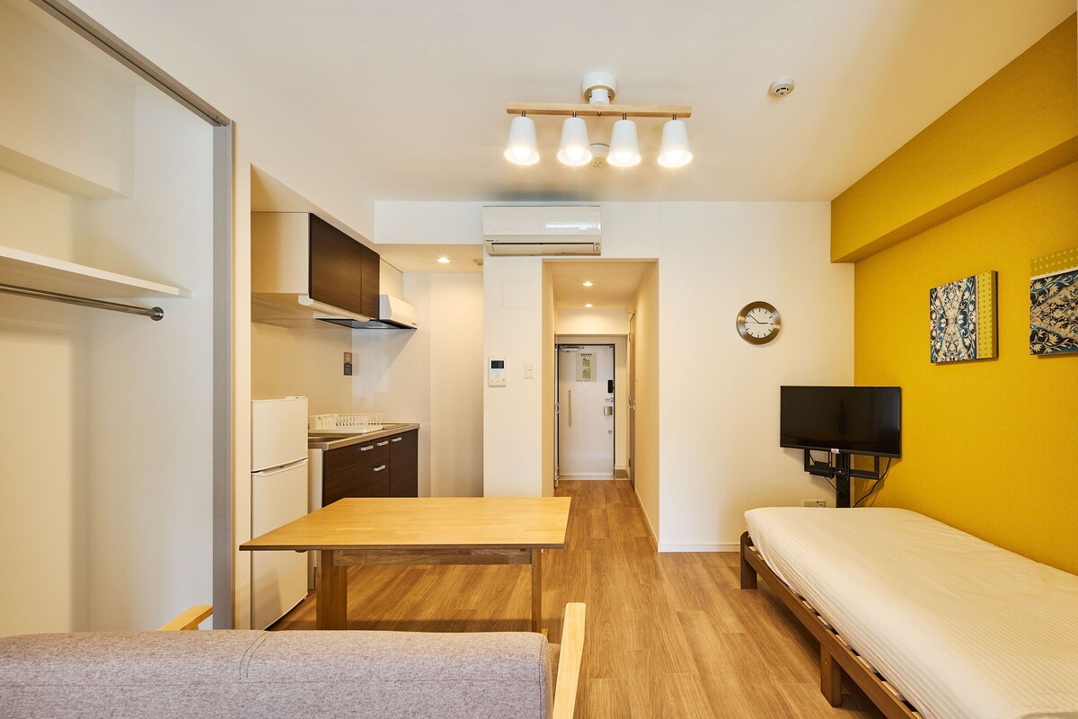 A compact room with a kitchenette, a bed, a TV, and a small table.