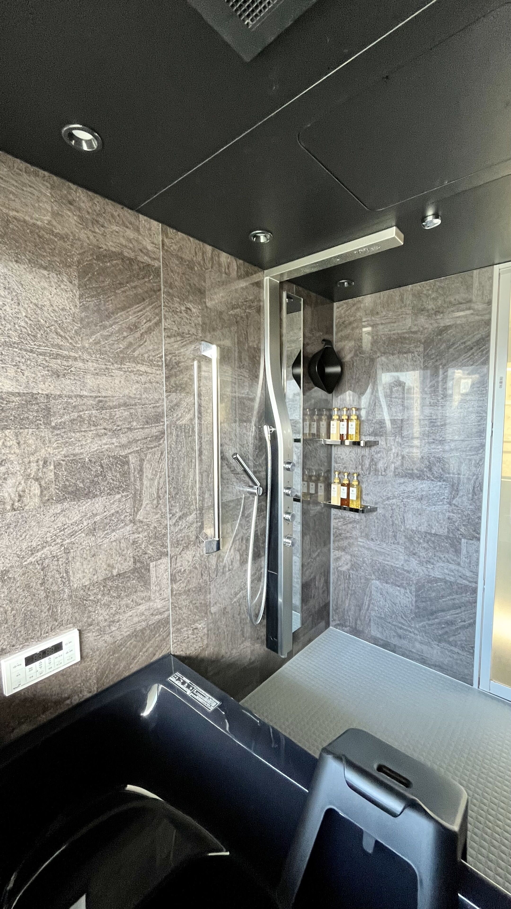 A modern bathroom with a large bathtub, a glass-enclosed shower, and a vanity with toiletries.