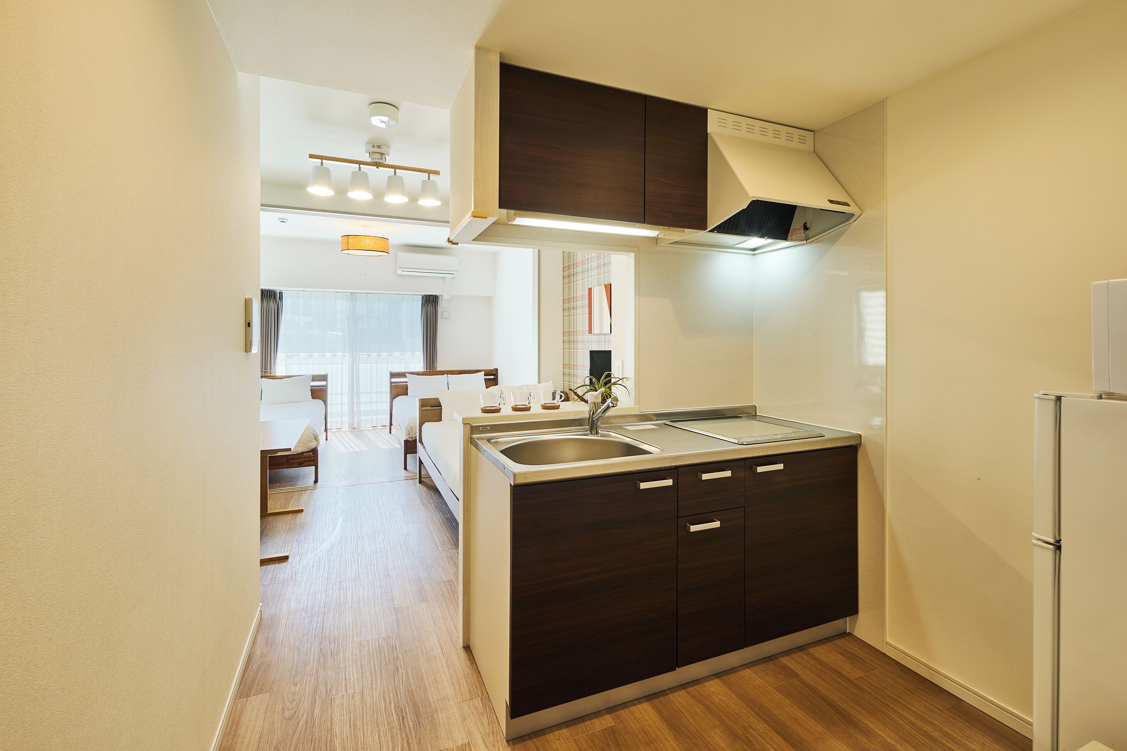 A compact kitchen with dark cabinetry, a stainless steel sink, and a built-in oven.