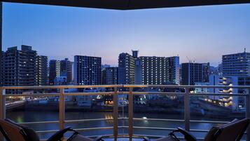 Un balcone con due sedie e vista sulla città al crepuscolo.