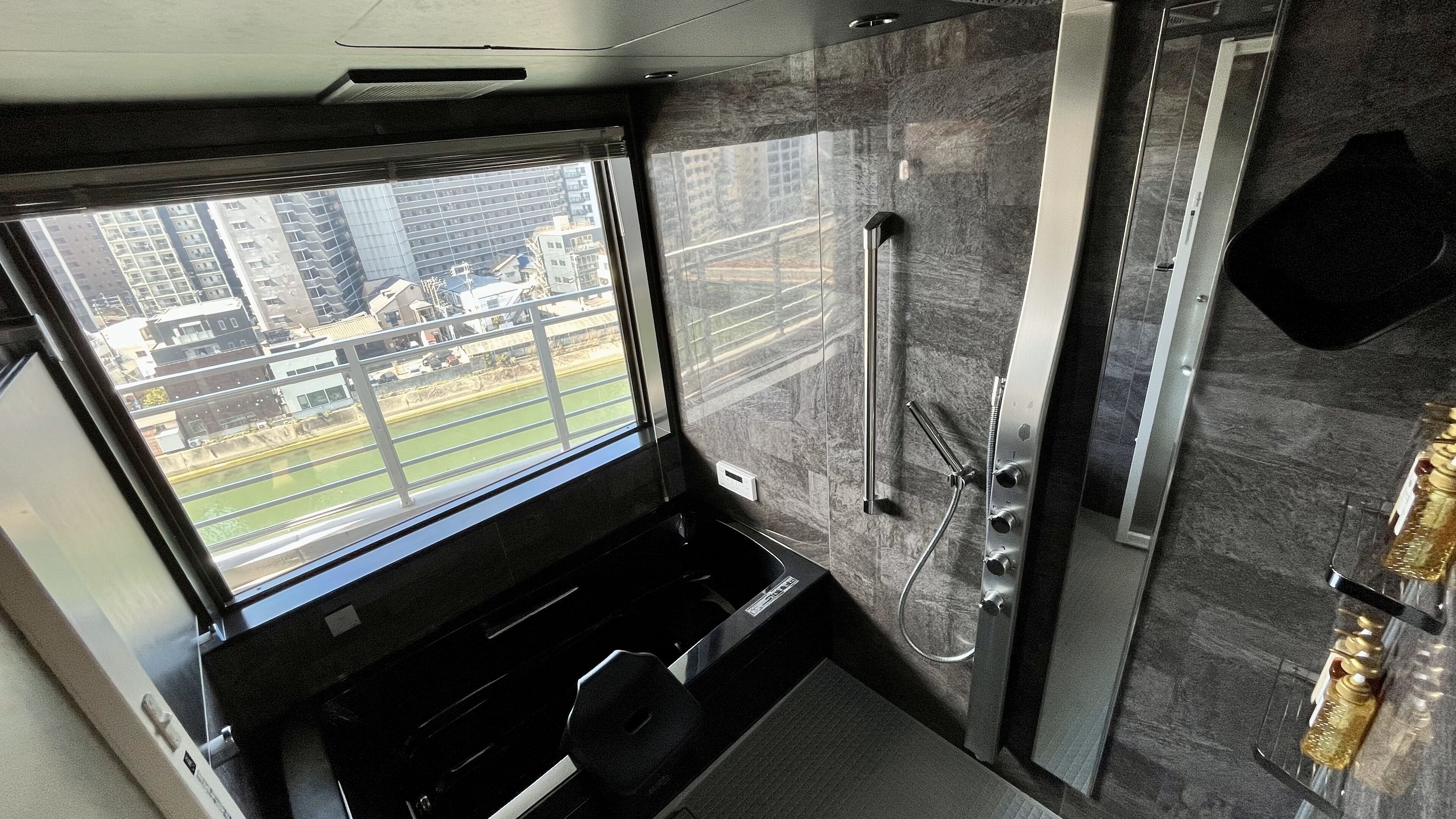 A modern bathroom with a large window, a shower, and a mirror.