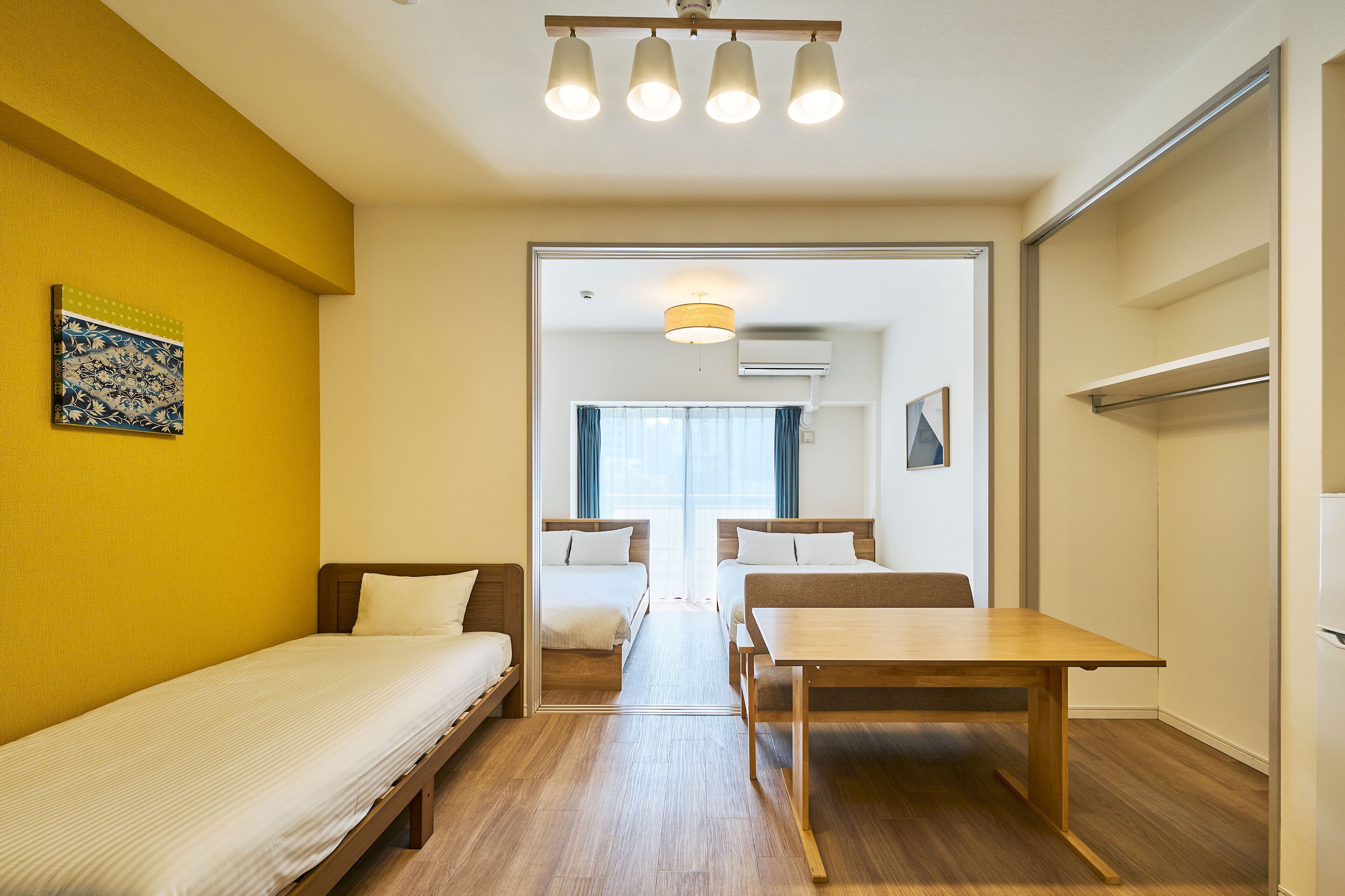A compact room with two single beds, a wooden table, and a mirror.