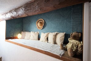 A cozy room with a wooden beam ceiling, a patterned wall, a bed with a white quilt, and a teddy bear on the bed. - Rare Cassis duplex apartment, 5 minutes from the beach and port on foot (Cassis)