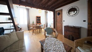 Un soggiorno accogliente con soffitto in legno, una zona pranzo con tavolo e sedie, e un grande specchio appeso al muro.