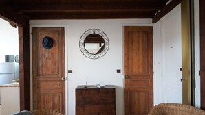 Una stanza con due porte in legno, uno specchio, un piccolo armadietto in legno e sedie in vimini.
