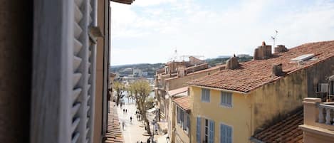 A view of a street with buildings, a river, and people walking.