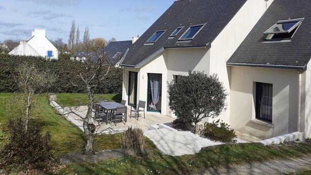 Ein modernes Haus mit Satteldach, einer Terrasse mit Gartenmöbeln und einem gepflegten Garten.