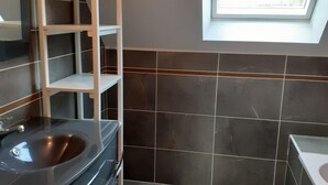 Ein modernes Badezimmer mit integriertem Waschbecken, einer Holztrennwand und einem Dachfenster.
