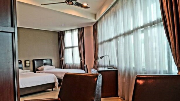 A hotel room with two beds, a desk, a chair, and a ceiling fan.