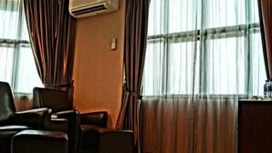 A hotel room with a large window, a desk, and two leather chairs.
