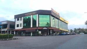 A modern building with a glass facade, a sign reading "KLUANG Rain Coffee," and a parking lot with several cars.