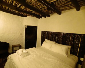 Une chambre à coucher avec un lit, une tête de lit en bois, une petite table de chevet et une porte.