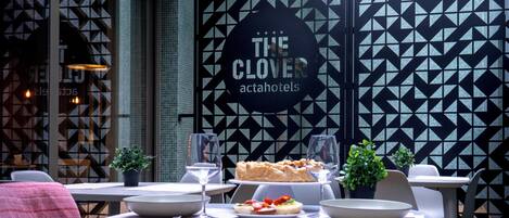 A dining area with tables set for meals, a menu board, and a decorative wall with geometric patterns.