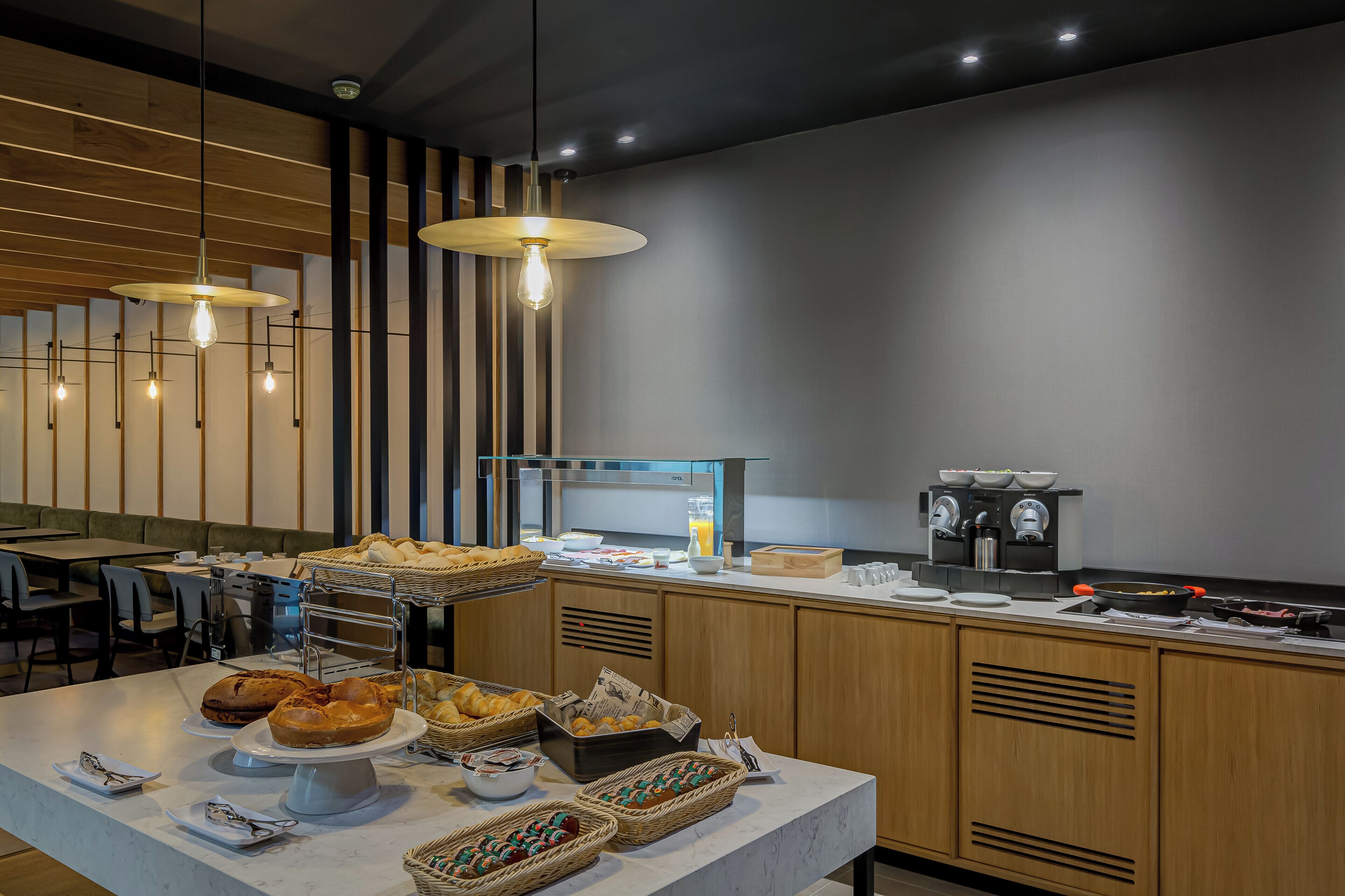 Un espace moderne dédié au petit-déjeuner, avec un buffet proposant une variété de produits de boulangerie et de boissons.