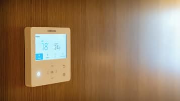 Un thermostat intelligent Samsung fixé sur un mur en bois, affichant les réglages de la température intérieure.