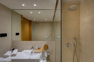 A modern bathroom with a large mirror, a shower, and a sink.