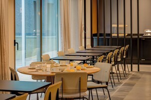 A dining area with round tables and chairs, breakfast items, and a view through large windows.