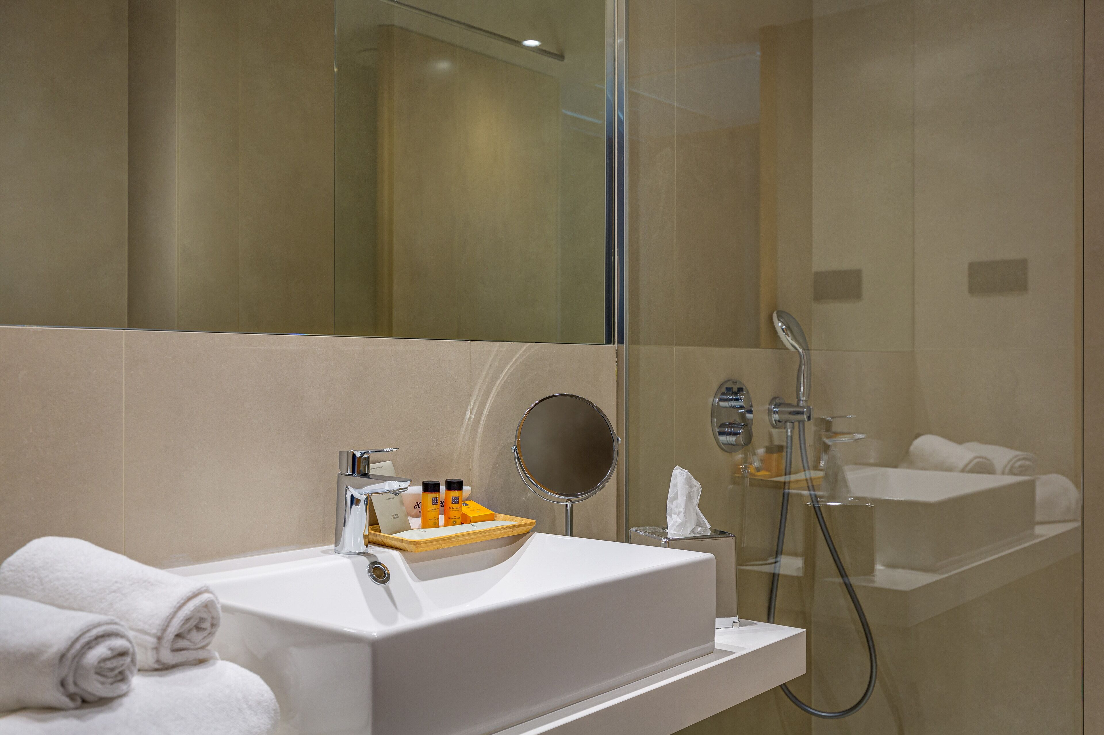 Une salle de bain moderne avec un lavabo blanc, un miroir et une douche.