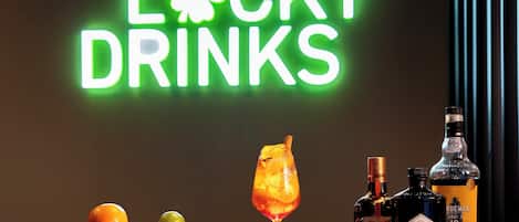 A neon sign reading "Lucky Drinks" with a cocktail glass and bottles of Hendrick's Gin and Cointreau on a table.