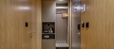A narrow hallway with wooden doors, a coat rack, a small seating area, and a security keypad.