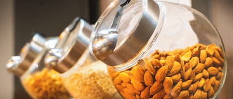 Una hilera de frascos de vidrio con tapas metálicas, cada uno con distintos tipos de nueces.