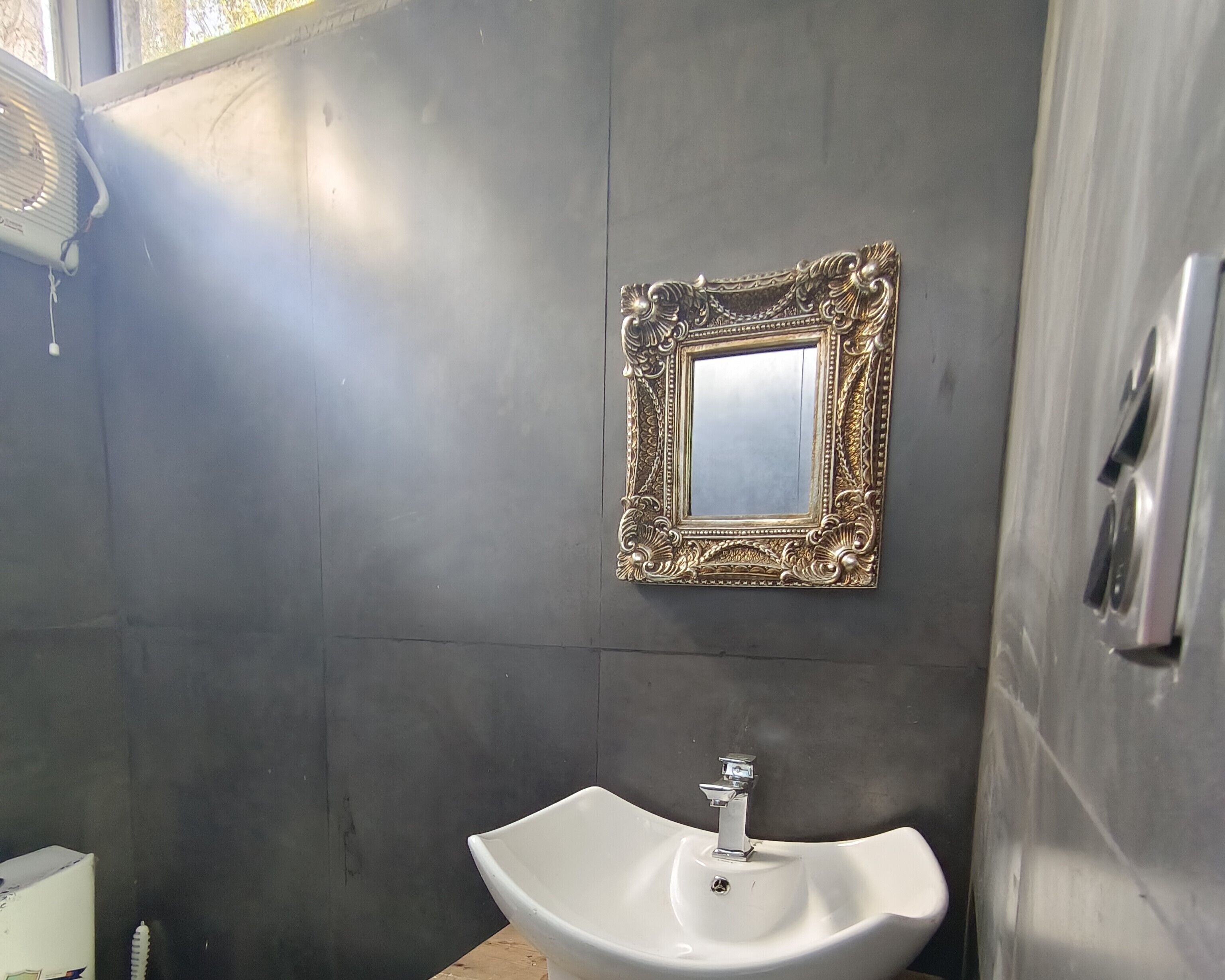 A bathroom with a white sink, a gold-framed mirror, and a towel rack.