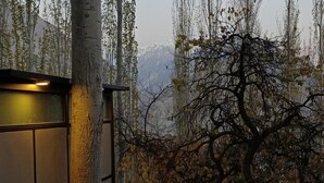 A building with a metal staircase leading to a glass door, surrounded by trees and a mountainous backdrop. - Zihin With Forest View - Cloud Nine And a Half (Karimabad)