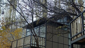A modern building with a wooden deck and stone walls, surrounded by trees. - Zihin With Forest View - Cloud Nine And a Half (Karimabad)