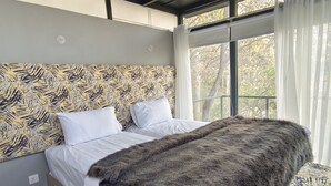 A bedroom with a patterned headboard, white bedding, and a large furry throw blanket. - Zihin With Forest View - Cloud Nine And a Half (Karimabad)