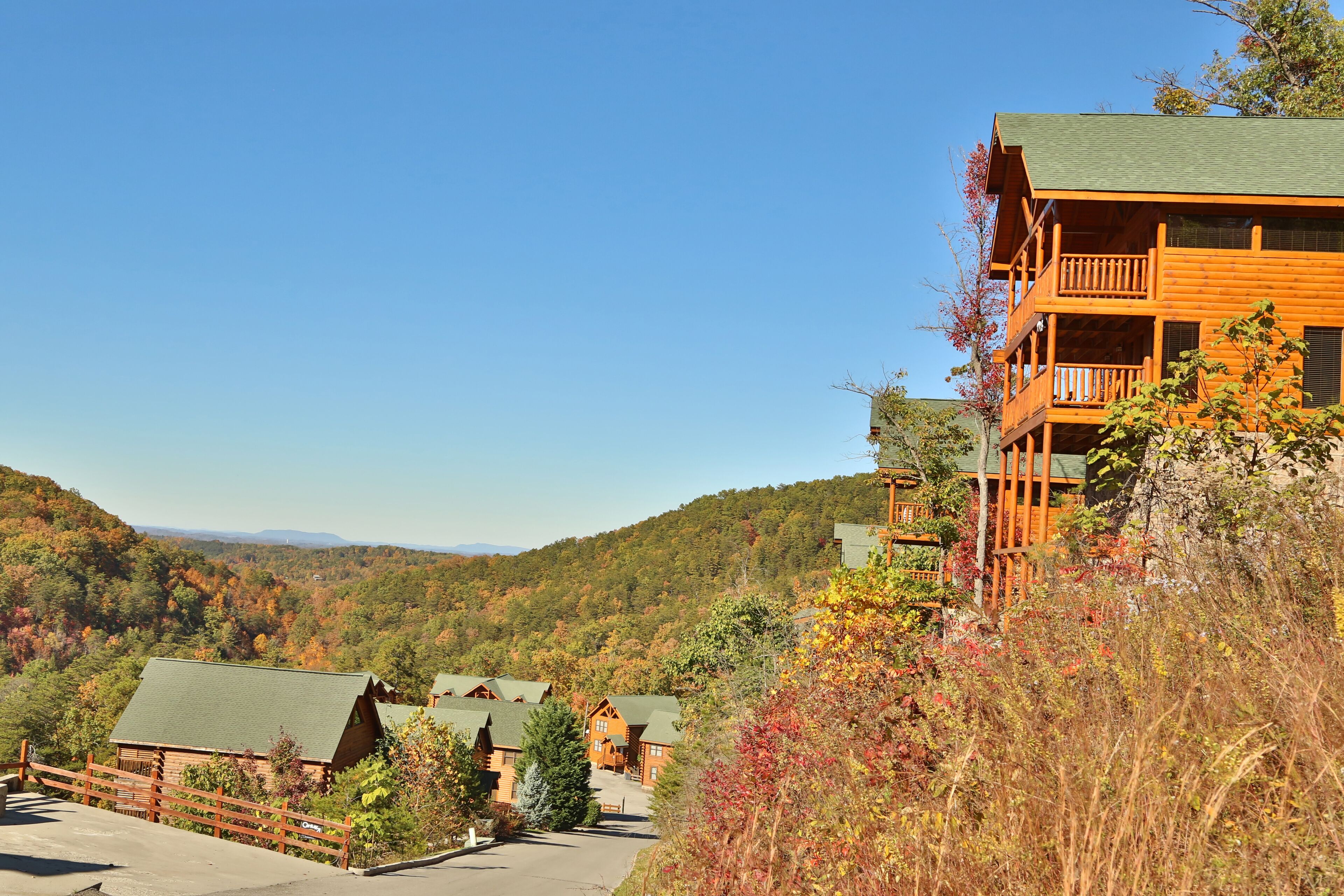 A lodge with multiple wooden buildings, a balcony, and a view of a forested valley.