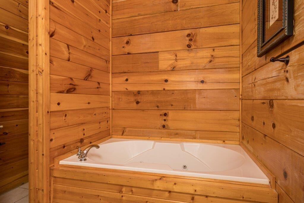 A wooden cabin with a white bathtub and a framed picture on the wall.