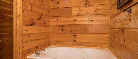 A wooden cabin with a white bathtub and a framed picture on the wall.