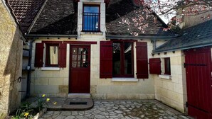 A traditional stone house with a red door, shuttered windows, and a small porch area. - Le Cottage des Chalands (Saint-Georges-sur-Cher)