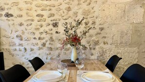 A wooden dining table set with plates, cutlery, and a vase with flowers. - Le Cottage des Chalands (Saint-Georges-sur-Cher)