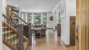 Een ruime woonkamer met een open haard, een trap en uitzicht op de omgeving.