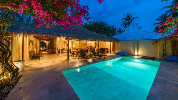 A pool area with lounge chairs and a thatched-roof structure. - Villa Matahari (Gili Meno)